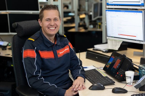Foto van brandweerman in uniform achter een bureau